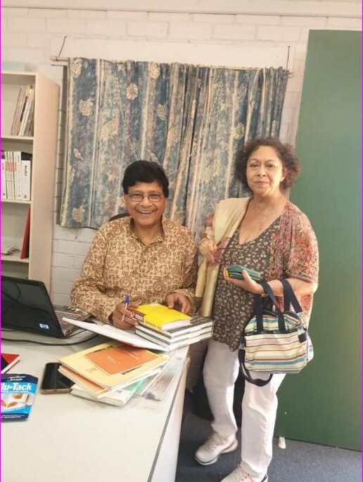 Author signing books at an Anandodhara literary event, standing beside a guest